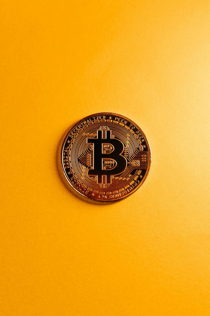 A detailed shot of a Bitcoin coin resting on a bold yellow surface, symbolizing digital currency.